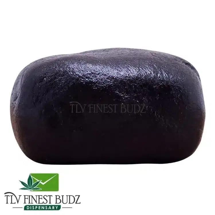 A glossy, black, pakistani hash on a white background, labeled as a product from TLV Finest Budz Dispensary.