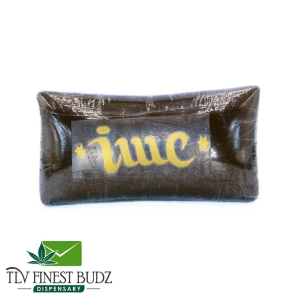 A thick, dark brown block of cannabis hashish, cut in half to reveal its textured interior, alongside the TLV Finest Budz logo.